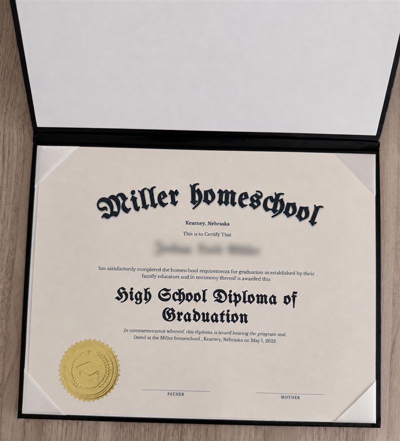 Black padded leather holder open, with a printed homeschool diploma held by ribbon corners and an embossed gold seal